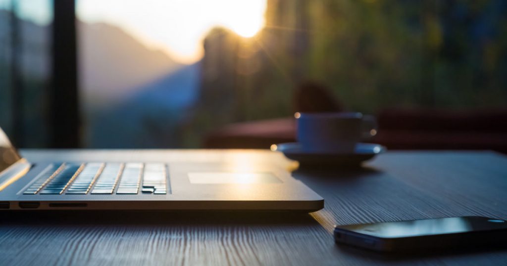 laptop on table with phone and coffee